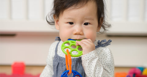 Baby chewing on plastic toy