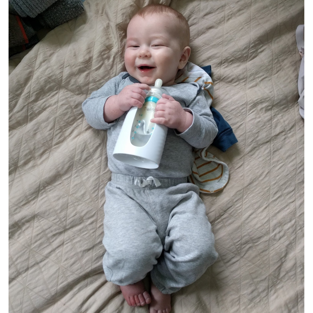happy four month old baby holding kiinde milk storage bag